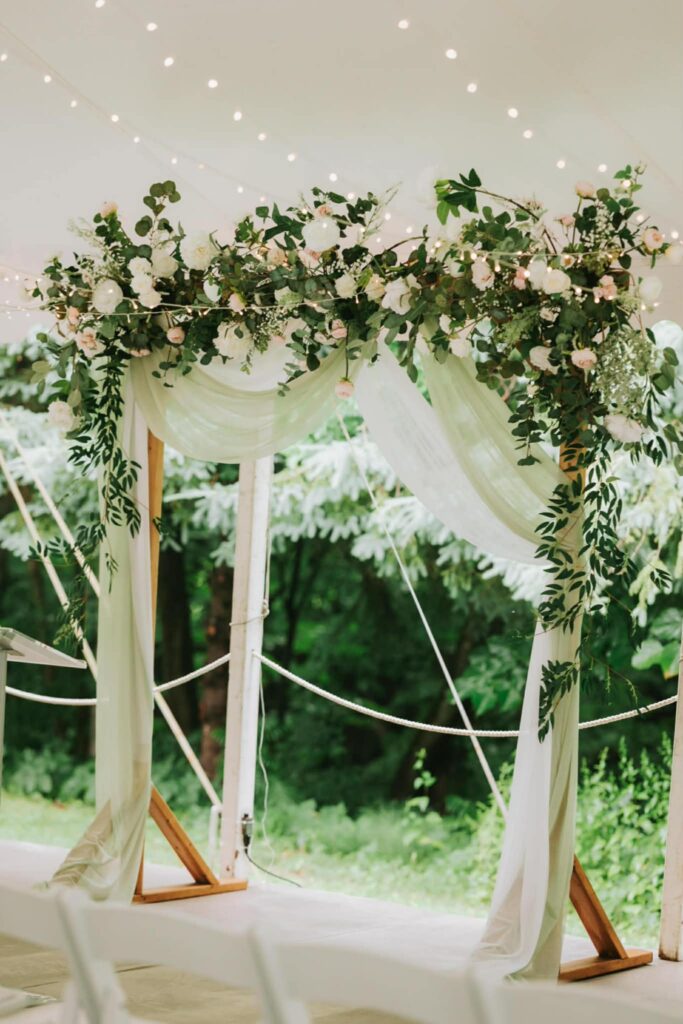 Floral Arch using lots of greenery, white and blush florals with white and green draping