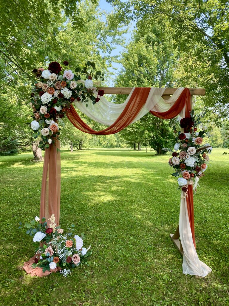 3-piece floral arch using burgundy, ivory, terracotta flowers.